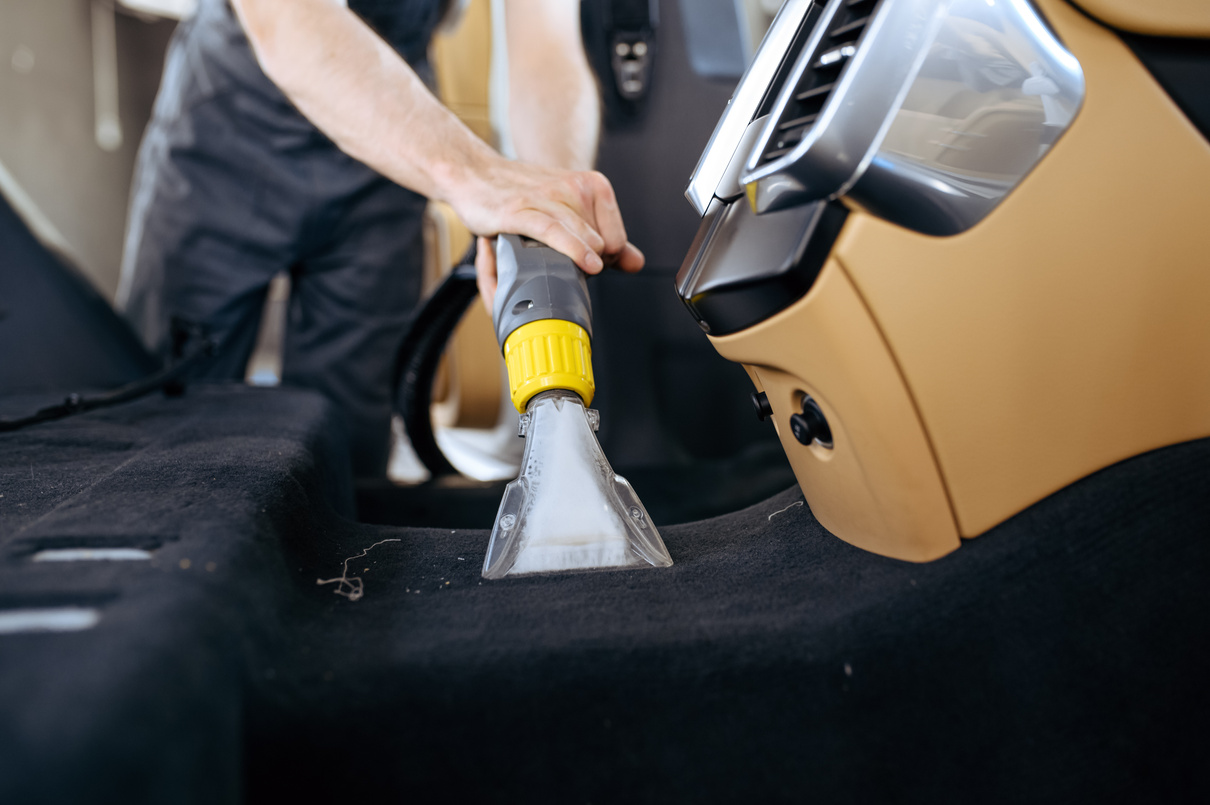 Worker Cleans Car Interior with Vacuum Cleaner